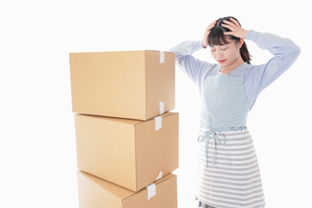 段ボールの前で悩む女性